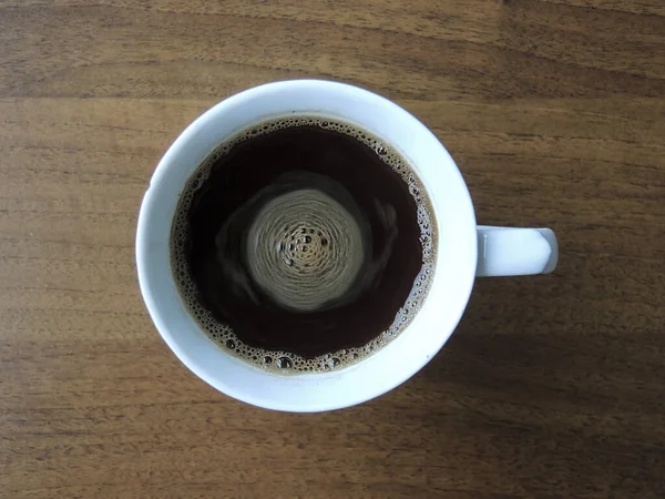 木のテーブルの上の白いカップに一人で攪拌熱いコーヒーのトップビュー — ストック写真