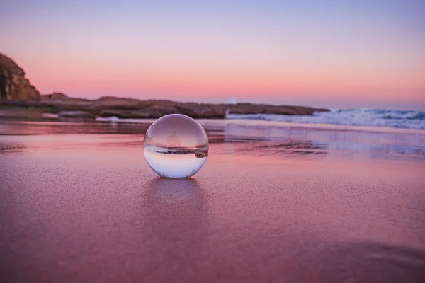 日落时分 一个清晰的水晶球落在海滩附近的沙滩上 这幅迷人的景象让人神魂颠倒 — 图库照片