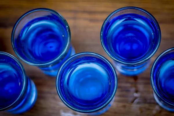 木製のカウンターにあるショットグラスでの青いドリンクのトップビュー — ストック写真