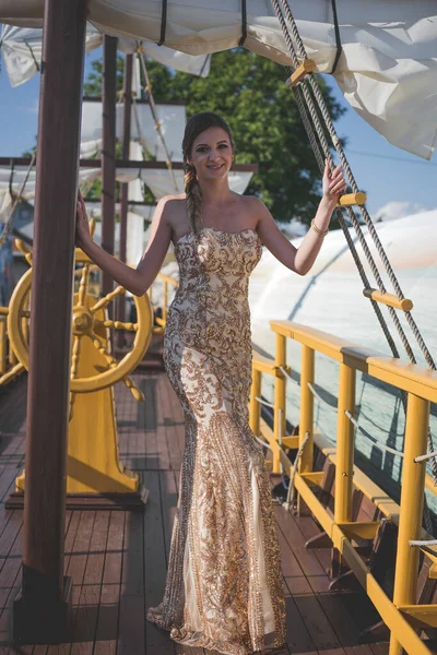 一个身穿晚礼服的年轻女子在船上摆姿势 — 图库照片