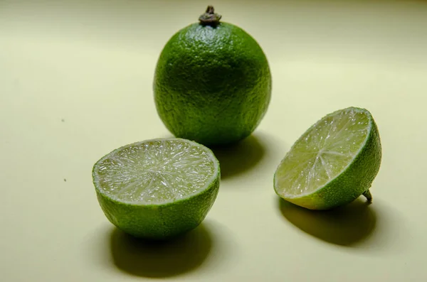 Citron Vert Entier Deux Moitiés Sur Fond Vert — Photo