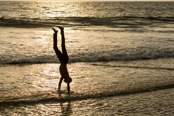 喀拉拉拉邦 2013年11月19日 一个男孩在海浪中倒立 可以被看作是夕阳西下的轮廓 — 图库照片