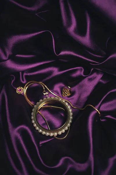 紫の絹の布の背景に金の宝石の垂直ショット — ストック写真