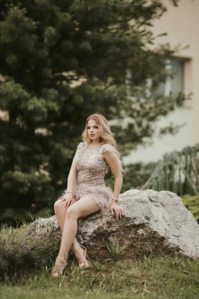 Молода Блондинка Позує Елегантному Бежевому Мереживному Платті Сидить Камені Саду — стокове фото