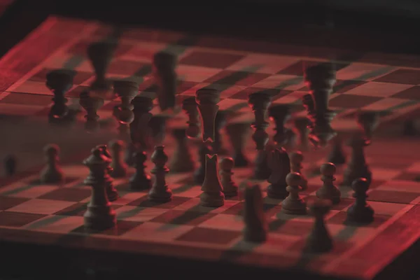 赤い光の下の暗い環境でのチェス盤その上のミラーに反射して — ストック写真