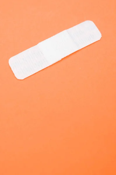 オレンジ色の背景に隔離されたバンドエイドの垂直ショット — ストック写真
