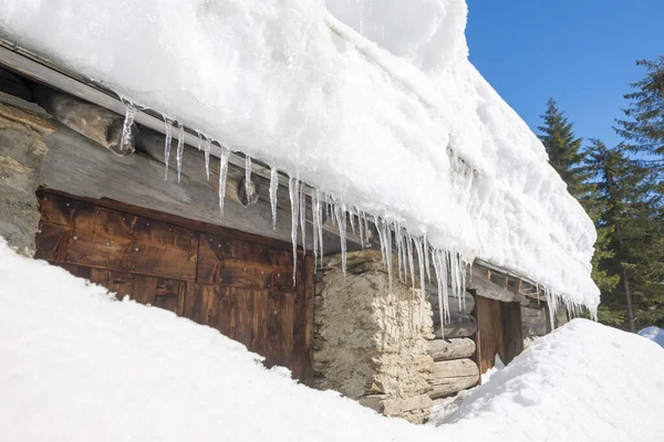 スイス グリソンズでの晴れた日の雪とつららの後ろの玄関ドア — ストック写真