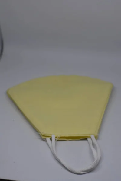 白い背景にCovid 19用の黄色のマスクの垂直ショット — ストック写真