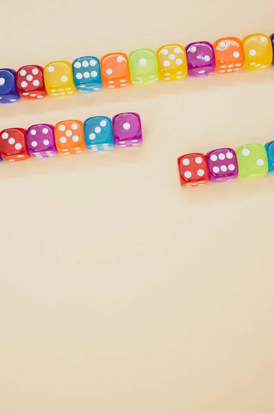 米色底色背景上孤立的一排彩色骰子中的一个垂直的镜头 — 图库照片