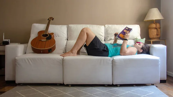 Oturma Odasındaki Kanepeye Uzanmış Gitar Okuyan Bir Kadın — Stok fotoğraf