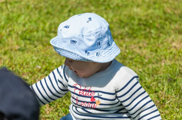 草の上に座っている帽子の中にかわいい幸せな男の子のクローズアップショット — ストック写真