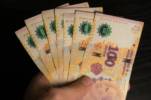 一只手拿着一堆阿根廷100比索钞票的特写镜头 — 图库照片