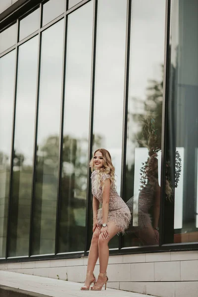 一个漂亮的金发女子在玻璃楼附近摆姿势的垂直照片 — 图库照片
