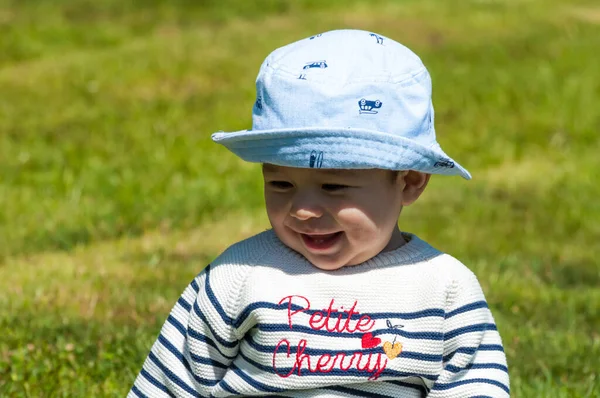 草の上に座っている帽子の中にかわいい幸せな男の子のクローズアップショット — ストック写真