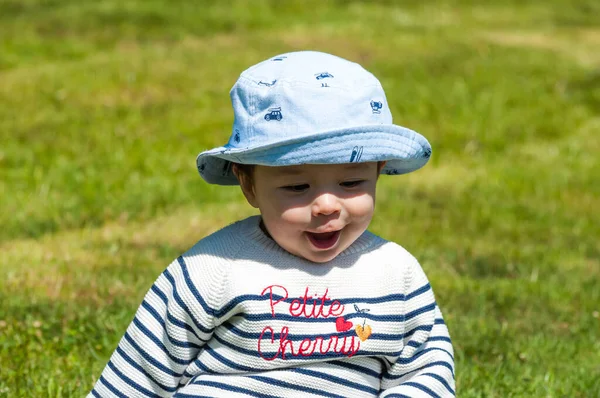 草の上に座っている帽子の中にかわいい幸せな男の子のクローズアップショット — ストック写真