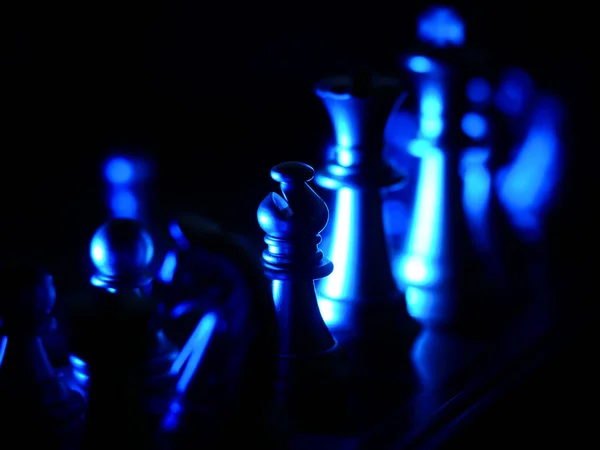 暗闇の中で青い光で照らされたチェスの数字の劇的なショット — ストック写真