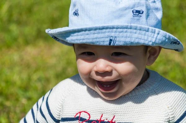 草の上に座っている帽子の中にかわいい幸せな男の子のクローズアップショット — ストック写真