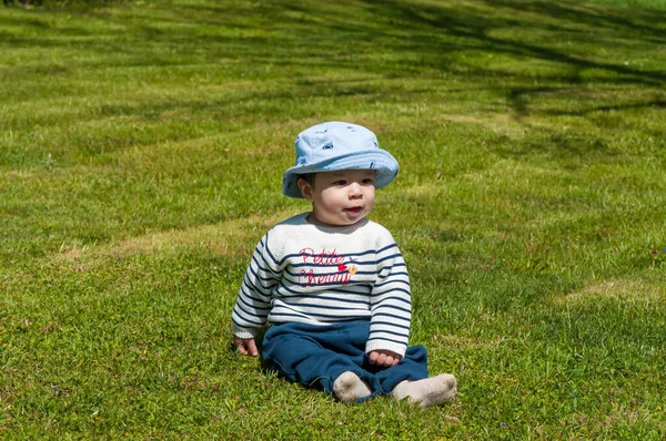 草の上に座っている帽子の中にかわいい幸せな男の子のクローズアップショット — ストック写真