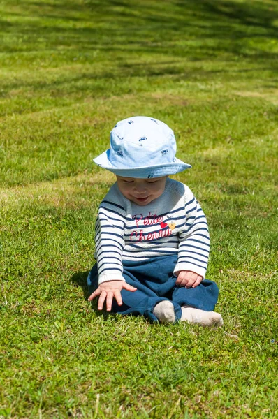 草の上に座っている帽子の中にかわいい男の子の垂直ショット — ストック写真