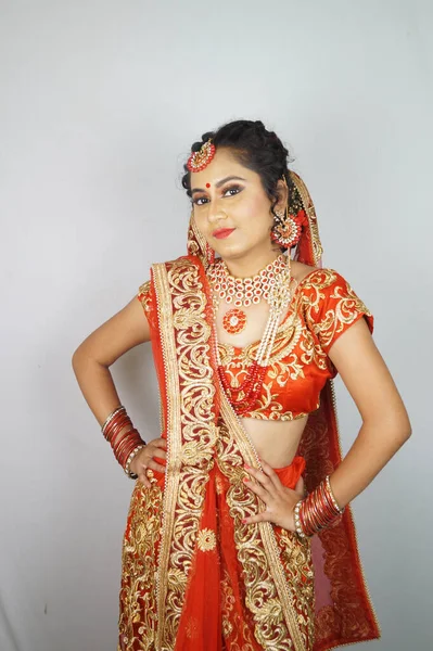 白い壁にポーズをとる伝統的な赤いサリーのドレスを着た美しいインド人女性 — ストック写真