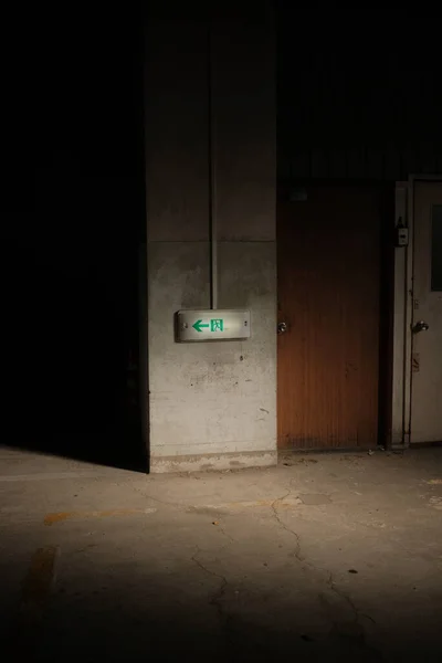 A vertical shot of a fire exit arrow sign on an abandoned building