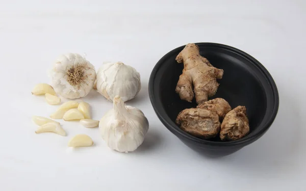 A closeup shot of garlic and ginger on a white surface