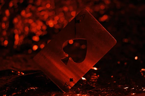 A closeup shot of an ace of spades metallic card isolated on the red, bokeh background