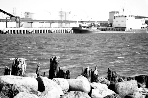 在港口和波涛汹涌的水面上有船只的港口的灰度照片 — 图库照片