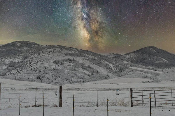 以栅栏为背景的银河穿越雪山的风景 — 图库照片