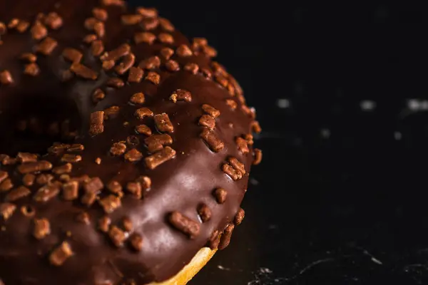 Eine Nahaufnahme Eines Schokoladen Donuts Mit Streusel Auf Schwarzem Hintergrund — Stockfoto