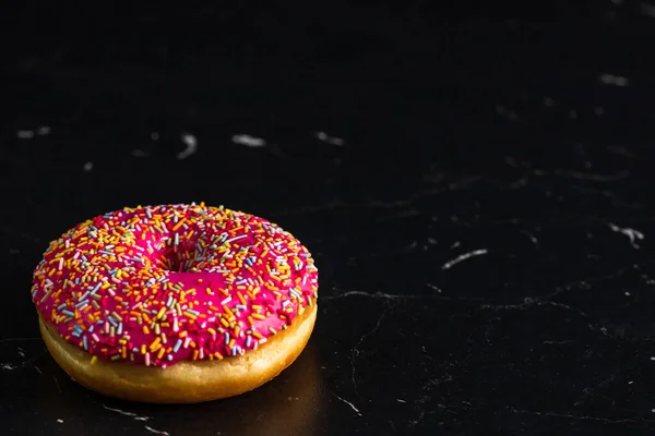 Eine Nahaufnahme Eines Glasierten Donuts Mit Streuseln Auf Schwarzem Hintergrund — Stockfoto