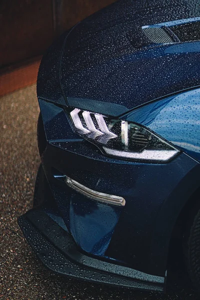 Вертикальный Снимок Синей Спортивной Машины Белой Фарой Покрытой Капельками Дождя — стоковое фото