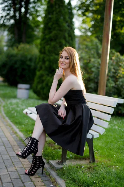 Una Joven Atractiva Mujer Vestido Negro Sentada Banco Posando Parque — Foto de Stock
