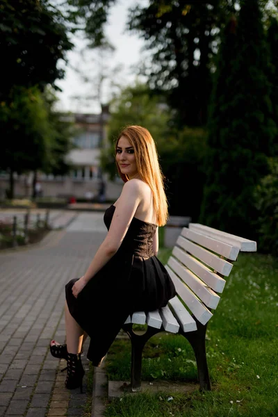 Parktaki Bankta Oturan Siyah Elbiseli Beyaz Bir Kadının Dikey Fotoğrafı — Stok fotoğraf