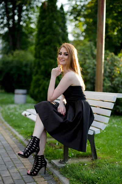 Uma Jovem Mulher Atraente Vestido Preto Sentado Banco Posando Parque — Fotografia de Stock