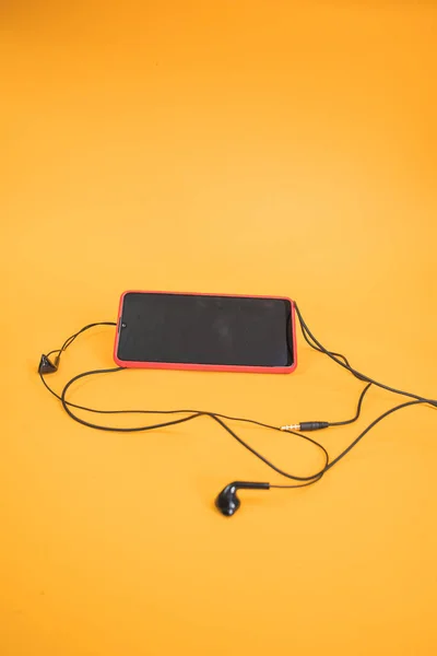 Eine Vertikale Aufnahme Eines Mobiltelefons Mit Kopfhörern Auf Gelbem Hintergrund — Stockfoto