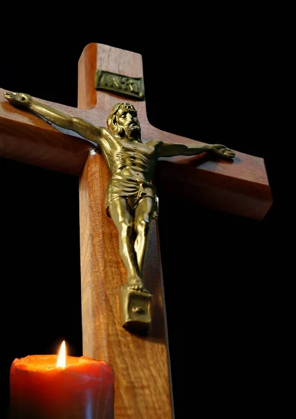 木製の十字架の下から見上げると 黒の上に孤立した前にろうそくが灯されている — ストック写真
