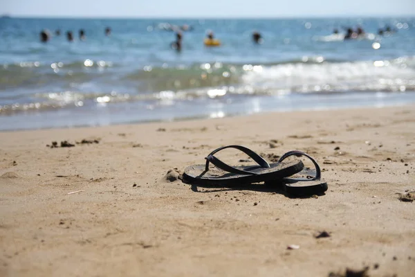 砂浜に黒いフリップフロップのペアのクローズアップショット — ストック写真