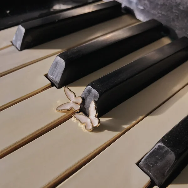 Pillangó Alakú Fülbevalók Közelsége Egy Zongorán Fények Alatt — Stock Fotó