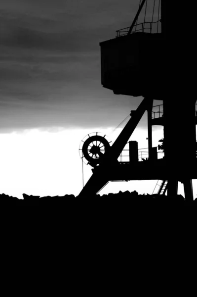 黑暗天空背景下的工业机器的黑白照片 — 图库照片