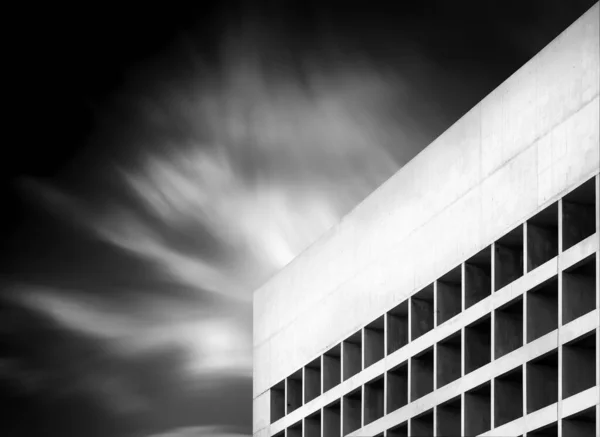 Egy Szürkeárnyalatú Felvétel Egy Modern Épületről Felhős Alatt Hosszú Expozícióval — Stock Fotó