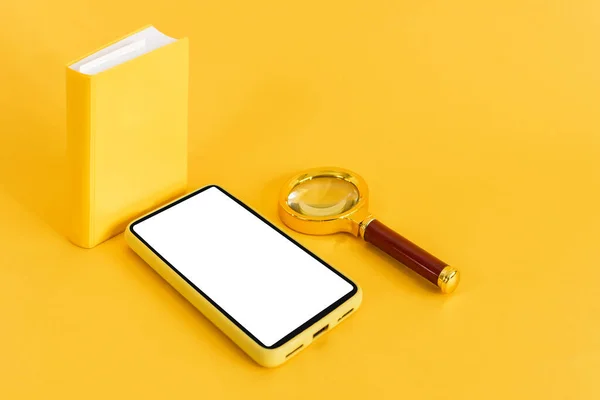 Small Book Magnifying Glass Smartphone Yellow Background — Stock Photo, Image