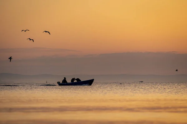Sylwetka Ludzi Łodzi Morzu Latające Ptaki Cudownym Kolorowym Zachodzie Słońca — Zdjęcie stockowe