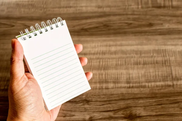 Female Hand Holding Notebook Wooden Desk — Stok fotoğraf