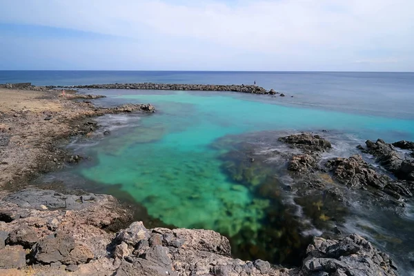 ランサローテ島 カナリア諸島 スペインの岩の多い海岸線に囲まれた澄んだターコイズブルーの水で美しい湾 ラグーンの長い露出 — ストック写真