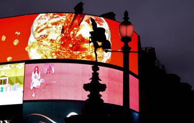 LONDON, UNITED KINGDOM - Aug 20, 2015: Digital commercial / marketing / advertising screens lit up in Piccadilly Circus London, with a silhouette of the angel statue of Anteros on screen clipart