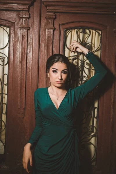 屋外でポーズをとる緑のドレスを着た若いエレガントな女性の垂直ショット — ストック写真