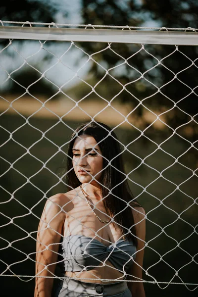 田园里一个穿着庄稼顶盖在排球网后面的年轻女子的肤浅的焦点 — 图库照片