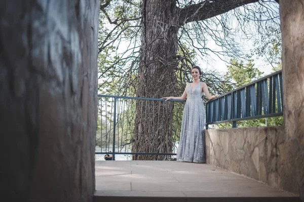 一个穿着灰色长裙 靠在花园栅栏上的成年女子 — 图库照片