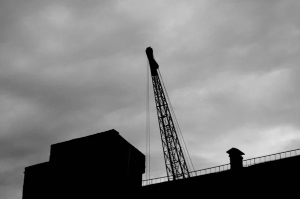Grayscale Shot Crane Building Background Cloudy Sky — Zdjęcie stockowe